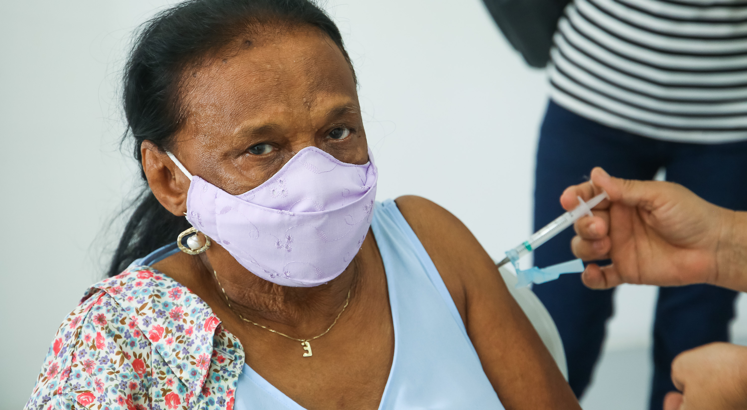 senhora de máscara sendo vacinada